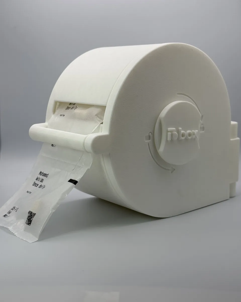 A white LioBox with a strip of labelled sachets coming out of its slot