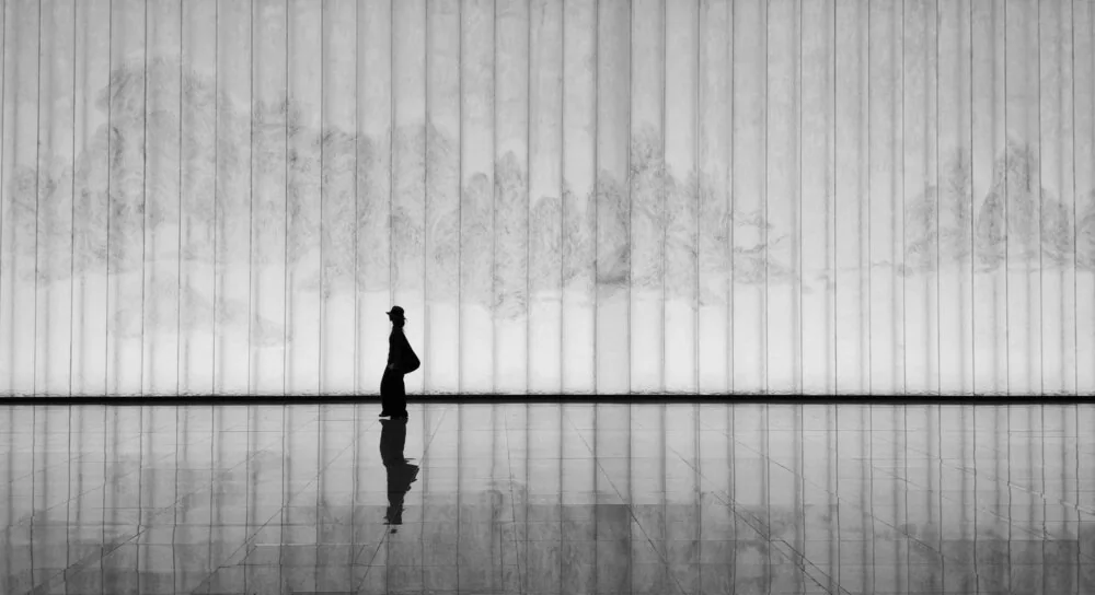 A person standing alone in a wide, empty room